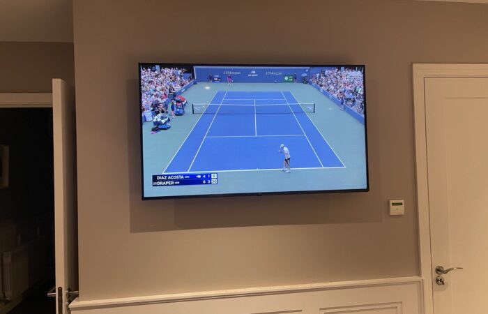 Large TV wall mounted flush in a living room, showing live tennis