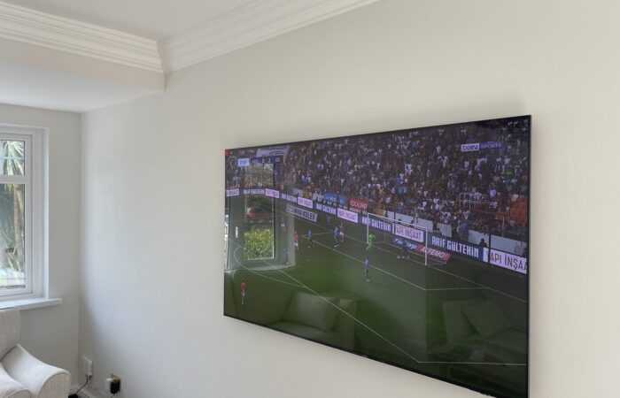 Spirit level on top of a freshly mounted TV confirming a perfectly level installation